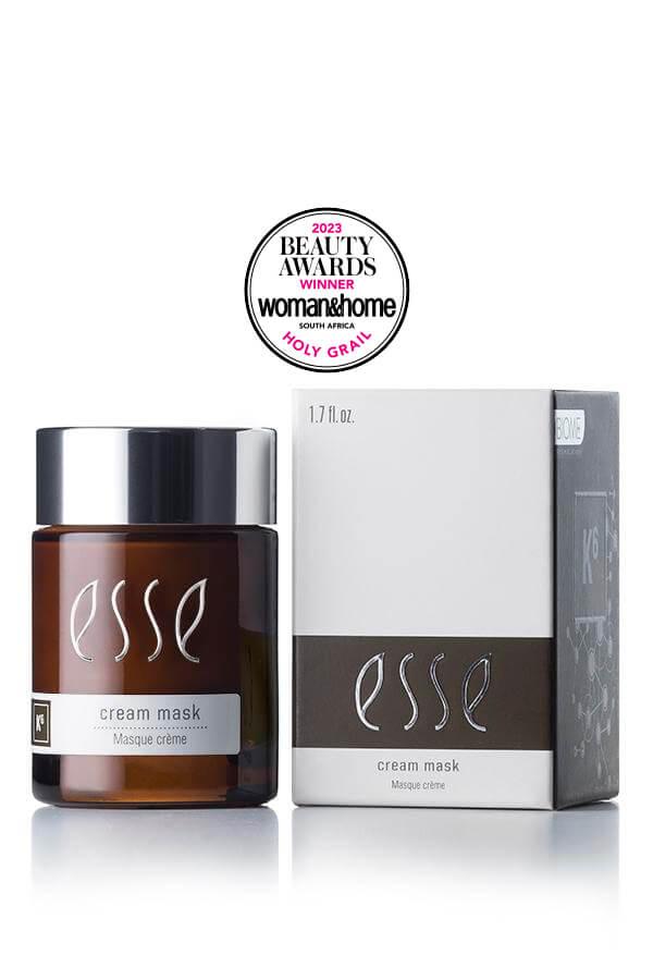 Image of the Award-Winning Esse Cream Mask, a skincare product in a brown jar with a silver cap, placed next to its white and grey box packaging. An award seal above proudly displays "Beauty Awards Winner 2023" by Woman & Home South Africa with "Holy Grail" mentioned below.